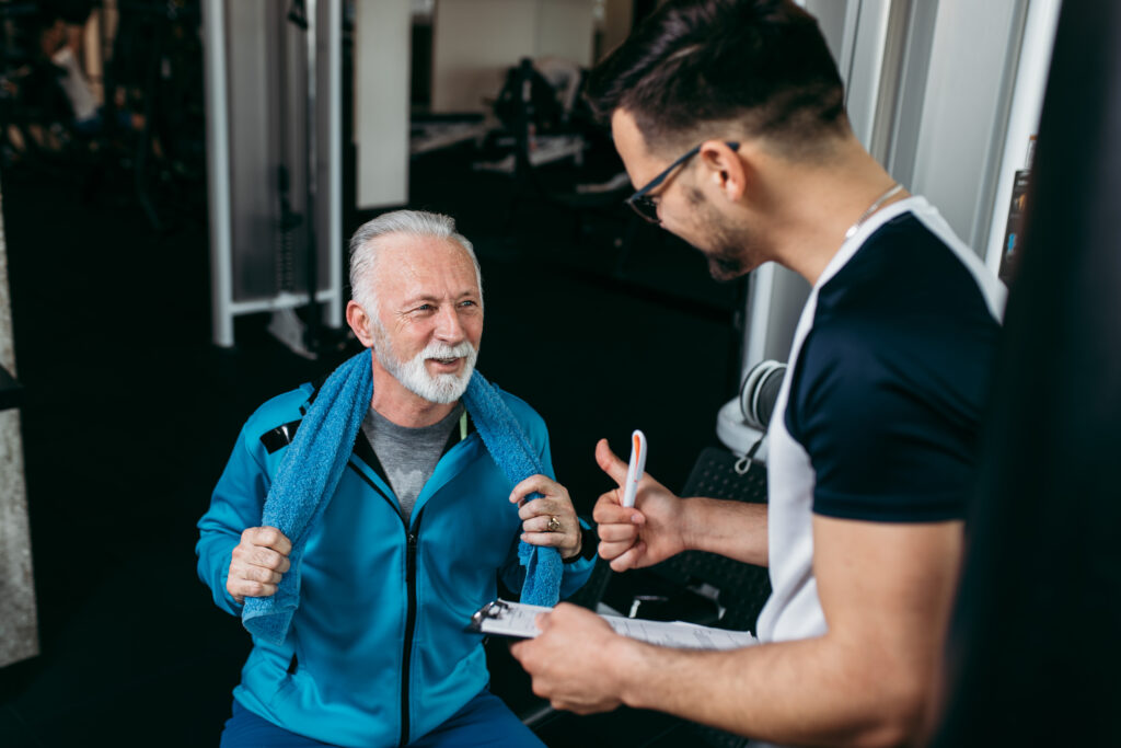 Senior man exercising in gym with his personal trainer.